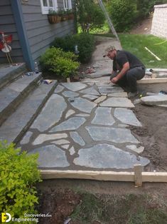 a man working on an outdoor patio with flagstone pavers laid out in front of the house