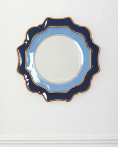 a blue and gold plate on a white wall with a black border around the edge