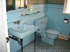 a blue bathroom with a toilet, sink and mirror