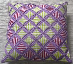 a purple and green pillow sitting on top of a bed