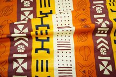 an orange, yellow and brown fabric with different designs on the top one has words written in bold black letters