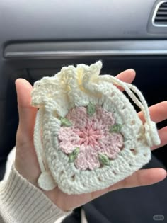 a hand holding a small crocheted bag in it's right hand,