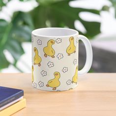 a yellow ducky mug sitting on top of a wooden table next to a book