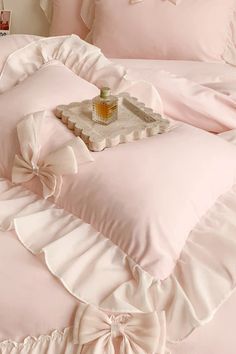 a pink bed with ruffles and a bottle of perfume on the pillow cover