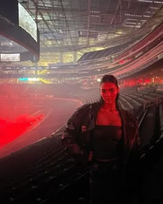 a man standing in the middle of an empty stadium with red lights on his face