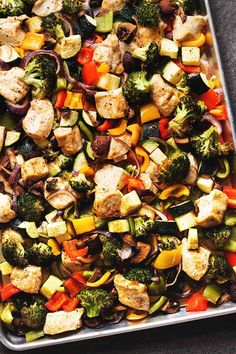 a sheet pan filled with chicken, broccoli and other vegetables on top of a table