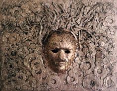 an intricately carved mask is shown in the middle of a piece of art that looks like it's made out of metal