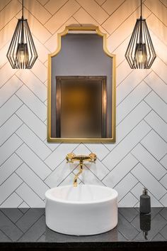 a white sink sitting under a bathroom mirror next to a wall mounted faucet