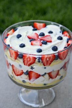 fresh berry trifle with whipped cream and blueberries in a glass dish on a table