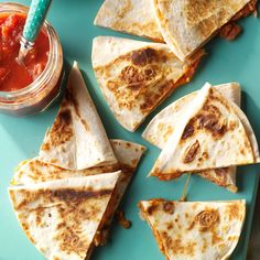 several tortilla slices on a blue plate with salsa in a jar next to them