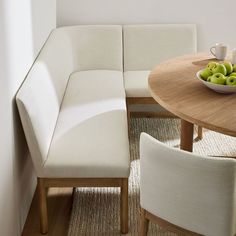 a bowl of green apples sitting on top of a wooden table next to a white couch