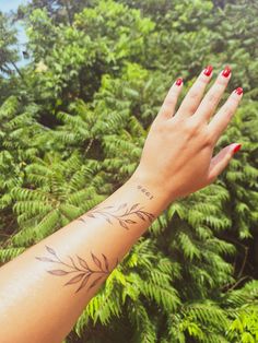 a woman's hand with a tattoo on it and some trees in the background