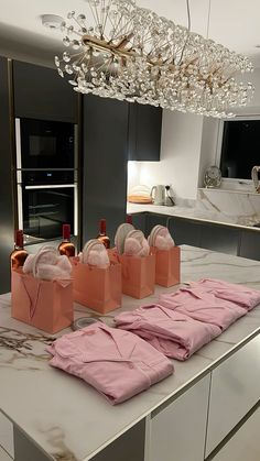 pink shirts and wine bottles on a counter in a kitchen with a chandelier