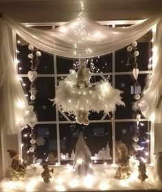 a window decorated with lights and snowflakes in front of a white curtained window