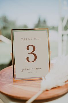 a table number is placed on top of a wooden plate with white feathers around it