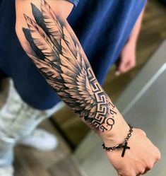 a man with a cross and wings tattoo on his arm