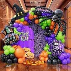 an entrance decorated with balloons and decorations for trick or treat halloween themed party in purple, green, orange and black colors