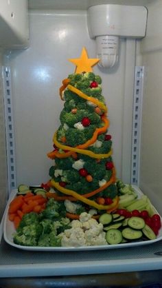 a christmas tree made out of veggies and carrots on a plate in an open refrigerator