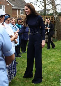 a woman standing in front of a group of people on top of a grass covered field