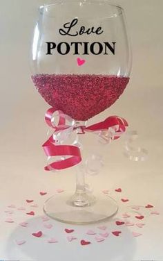 a wine glass with the word love potton on it and hearts around it, sitting on a table