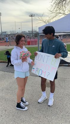 a man and woman standing next to each other holding a sign that says don't be humming pom pom