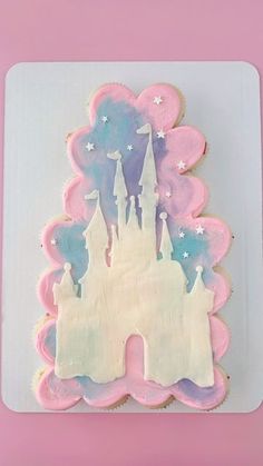 a frosted cake shaped like a castle on top of a pink plate with stars and clouds