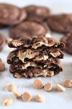 chocolate cookies with peanut butter on top are stacked up next to each other and scattered peanuts