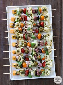 an appetizer is served on skewers with tomatoes, olives and mozzarella