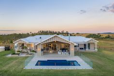 an aerial view of a house with a swimming pool in the foreground and green grass on the other side