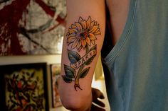 a woman with a sunflower tattoo on her arm and the word love is written in cursive writing