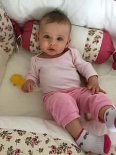 a baby sitting on top of a bed next to pillows