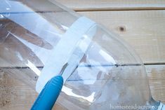 a plastic bottle with a blue handle and some tape on it sitting on a wooden table