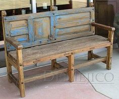 an old wooden bench sitting in front of a store window with blue paint on it