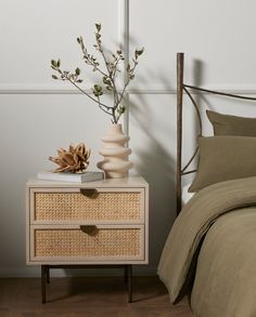 a bedroom with a bed, two nightstands and a plant on the end table