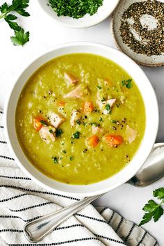 two bowls filled with soup and garnished with parsley next to spoons