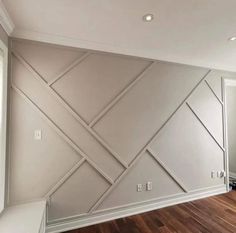 an empty room with wood floors and white walls, painted in light gray color on the wall