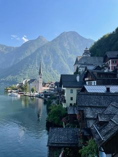 a lake surrounded by mountains and buildings with a church in the middle on one side