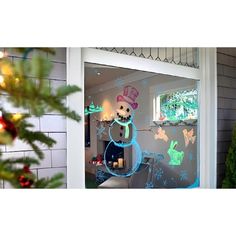 a snowman is seen through the window of a house with christmas decorations on it