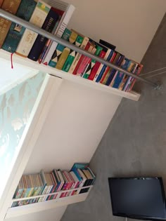 a bookshelf filled with lots of books next to a flat screen tv mounted on a wall