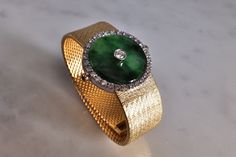 "Fine watch bracelet set with a jade donut and accented with diamonds in 18k. The donut is a deep green Omphacite jade, in parts dark and light like a globe lit. This jewel borrows the perfect finish of a Vacheron watch, its Omega straps in original burnished solid gold. More than a conversion piece, this bracelet could not have been refined to a sleeker layout. At 2cm, the donut is considered big yet its size is offset by the straps, and vice versa. The straps though wide feel made for its cent Green Polished Jewelry For Evening, Polished Green Jewelry For Evening, Green Polished Evening Jewelry, Green Polished Finish Evening Jewelry, Luxury Jade Jewelry, Formal Round Jade Jewelry, Elegant Green Diamond Watch For Formal Occasions, Timeless Green Jewelry For Evening, Timeless Green Evening Jewelry