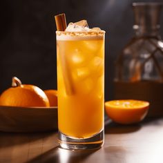 a tall glass filled with an orange and icey drink next to some oranges