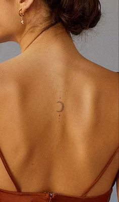 the back of a woman's neck with a crescent tattoo on her left shoulder