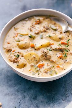 a bowl of soup with potatoes and meat in it on top of a blue surface