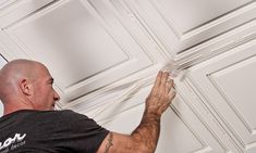 a man is painting the ceiling with white paint