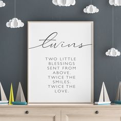 a white framed poster on top of a dresser next to a wall with clouds above it