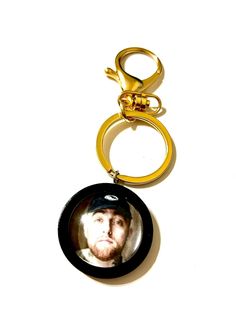 a man's face is shown in the middle of a keychain that has a ring attached to it