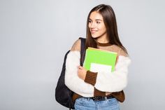 a young woman is holding a book and smiling