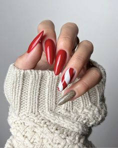 a woman's hand with red and white manies on it, holding onto a sweater