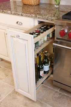 an open cabinet in the middle of a kitchen with wine bottles and other condiments