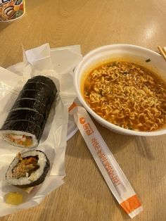 a bowl of ramen, roll and chopsticks on a table